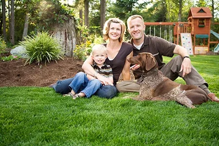 family sitting in grass with dog 